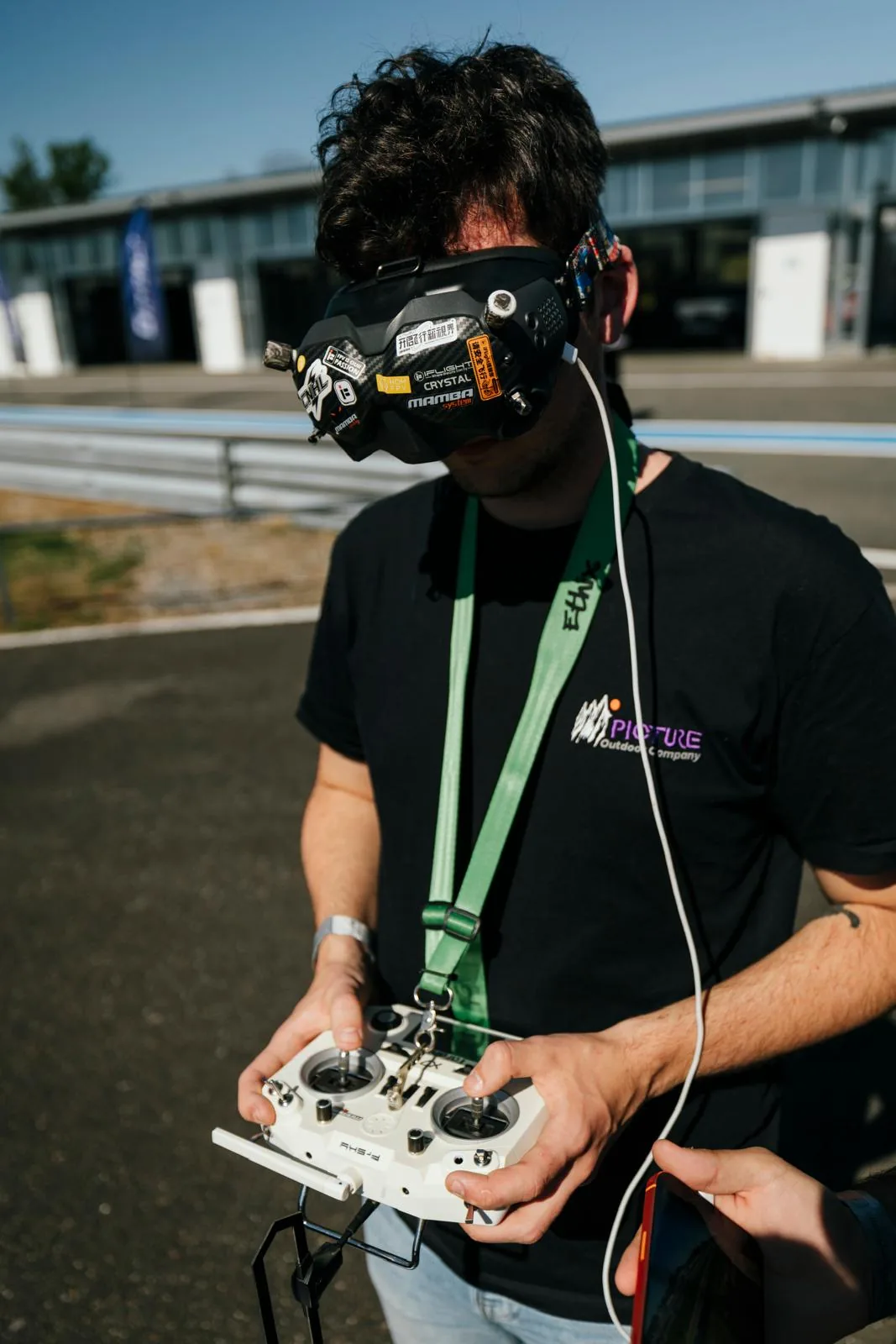 Théo, télépilote DRONEFLY17, pilote son drone FPV au casque en bord de piste sur un circuit automobile